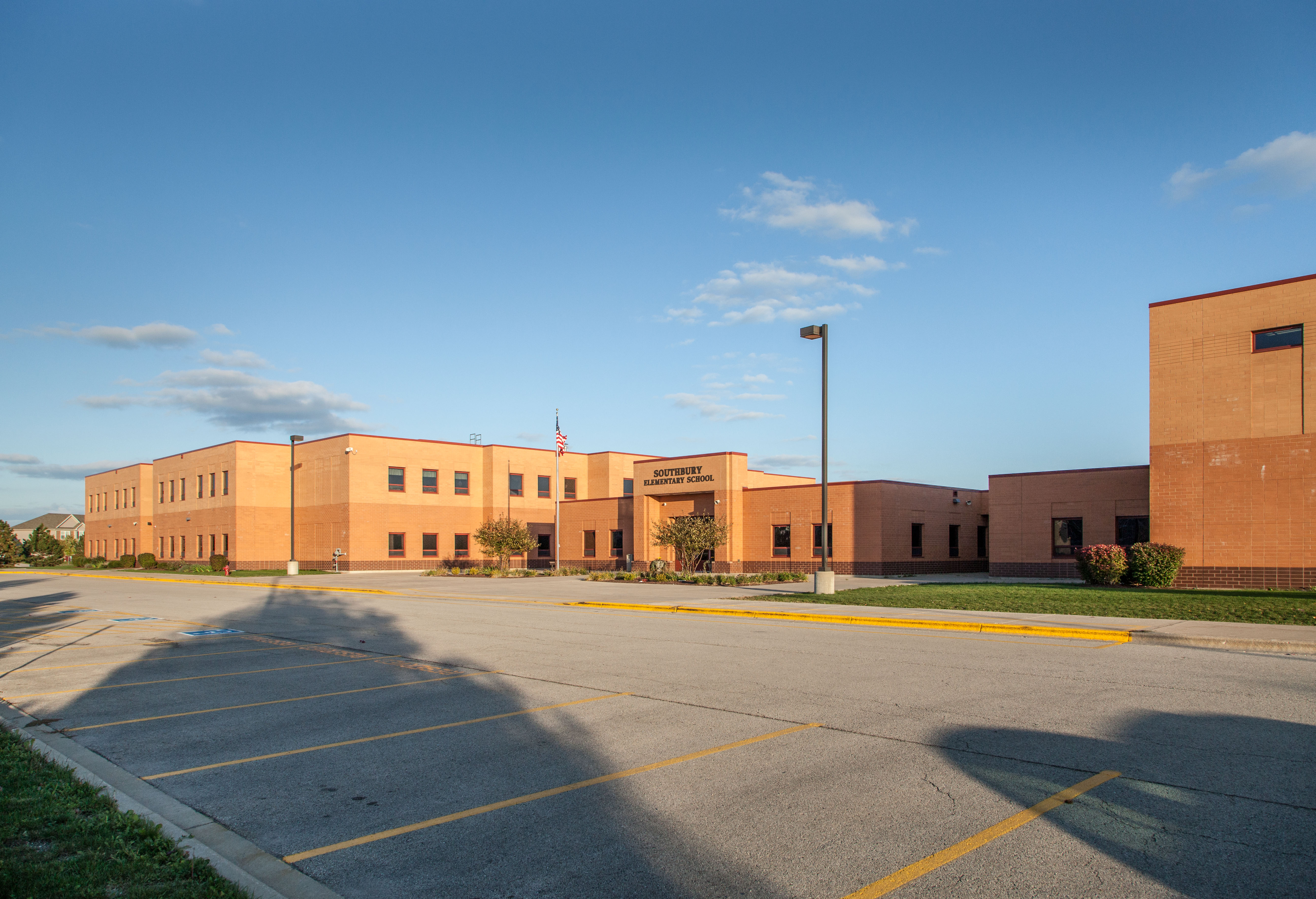 Southbury building front with empty parking lot, building entrance, and blue sky. 